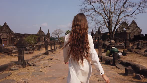 Young woman walking in Vat Phou ruined Khmer Hindu Temple complex. Ancient religious culture. Laos