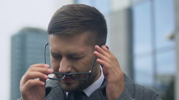 Young Man Taking Off Glasses and Rubbing Temples, Suffering High Blood Pressure