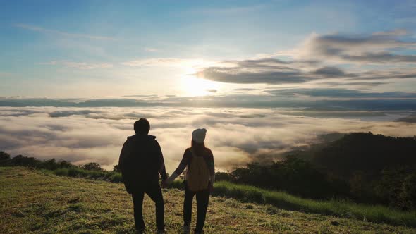 Young couple travelers looking at the sunrise and the sea of mist