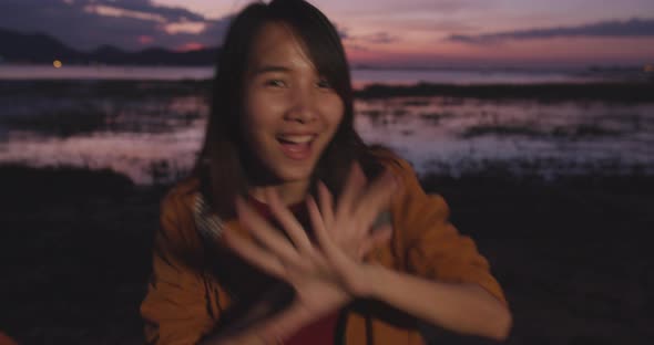 Asian lady with backpack feeling fun dancing smile to camera in camping on beach at night. alt