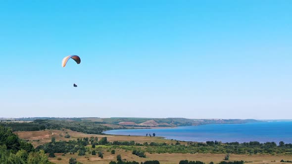People Are Flying Over the Land and Water on the Paraplane. Man Paragliding. Beautiful Nature alt