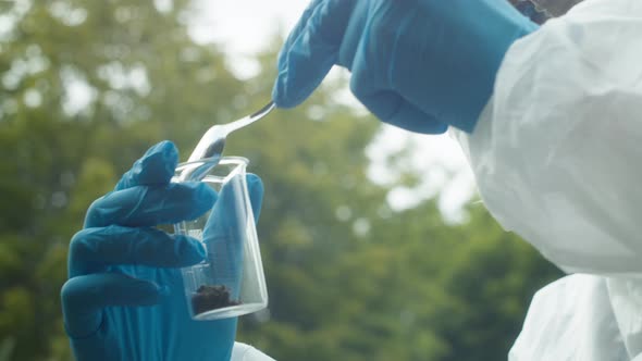 Chemist Taking Soil Analysis Using Flask and Little Shovel Wearing Protective Suit and Gloves Sample alt