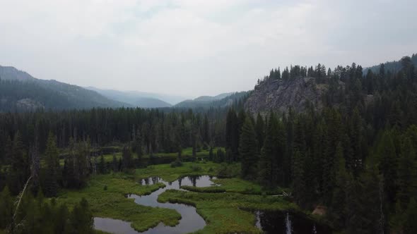 Crane drone shot of the Payette River in a forest in the Idaho wilderness. This stunning, smoky 4K c alt