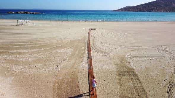 Beautiful romantic woman walking on wooden path to  the beach in summer vacation. Magganari beach. I alt