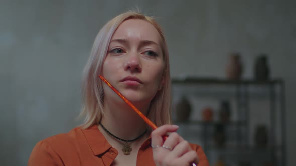 Thoughtful Female Painter Working on Artwork in Workshop alt