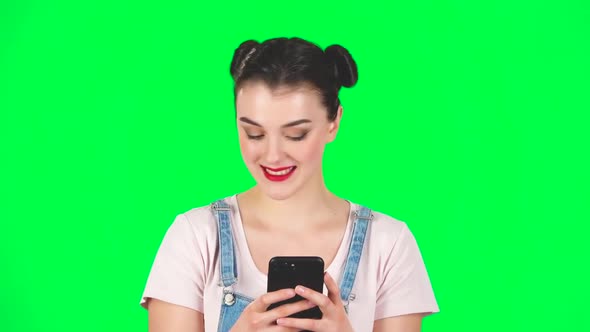 Young Smiling Woman Texting on Her Phone on Green Screen, Slow Motion alt