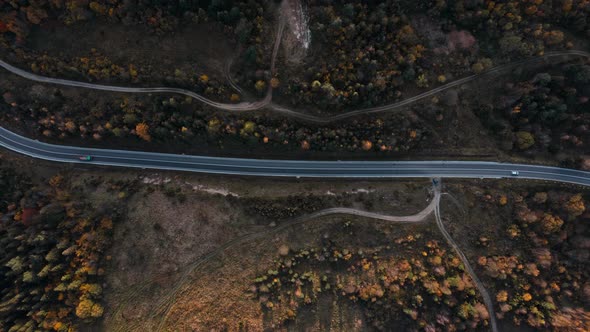 Aerial Top Down Winding Curving Mountain Road Between Hills Green and Orange Woods alt