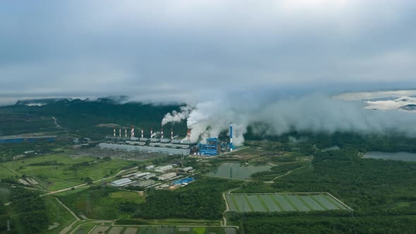 Aerial view over coal-fired power plant at sun dawn with smoke from cooling,