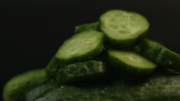Sliced Green Cucumbers Rotate On A Black Background