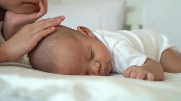 Asian Family of Cute Little Sister Touching Newborn Baby Boy Brother on Bed alt
