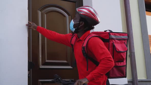 African rider man delivering meal to customers home with electric bicycle alt