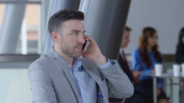 Young businessman using cell phone in office lobby