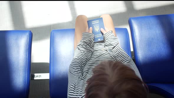 Sad Ukrainian Child Refugee at the Airport with a Passport in His Hands alt