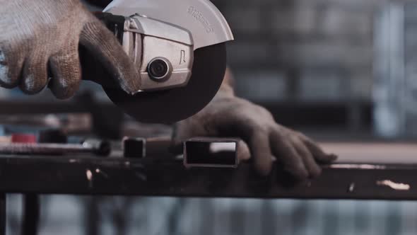 Manufacturing Plant  Man Worker Cutting the Part of Metal Detail with Angle Saw alt