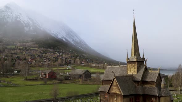 Lom Medieval Stave Church With Roof Detail Viking Symbol Against Misty Snow Mountains In Norway. Aer alt