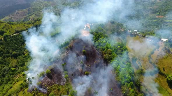 Aerial view of Bush fire Deforestation burning and smoking, in rainforests of Queensland, sunny day, alt