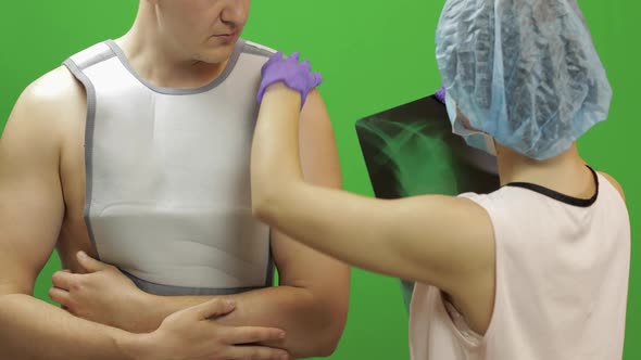 Man with Shoulder Injury. Nurse Examines X-ray. Bandage for Fixing Shoulder alt