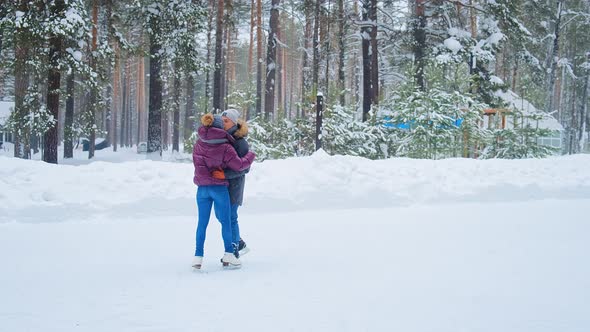 Girl and Guy Skate and Hug on Outdoor Rink in Winter Park