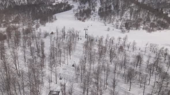 Flying over rope-way with gondolas at mountain resort Crystal Park in Bakuriani. Snowy winter day. alt