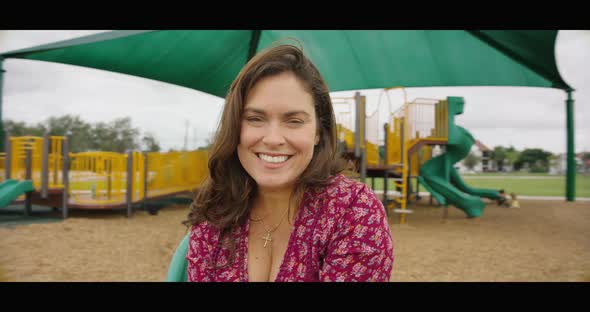 Slow Motion of Woman at Merry Go Round Smiling and Lifting Arms Up in Happiness alt