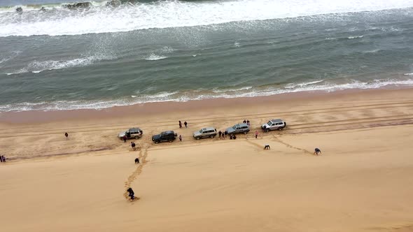 reveal shot of cars on the beach next to a huge dune in the Namib desert alt