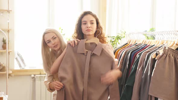 Curious and Attractive Young Women in an Ecological Shop Choosing Between Various Clothes
