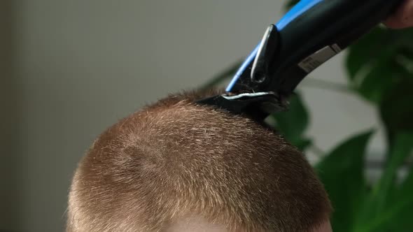 A Man is Getting a Haircut with an Electric Clipper at Home
