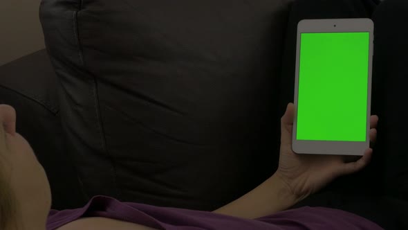 Woman holding silver tablet with greenscreen display 4K 2160p UHD footage - Female relaxing while lo