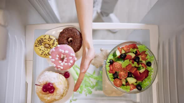 Woman's hand pushes aside unhealthy food and chooses green salad.