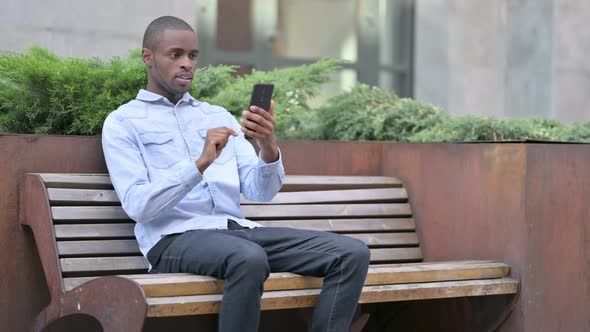 Ambitious African Man Celebrating Success on Smart Phone alt
