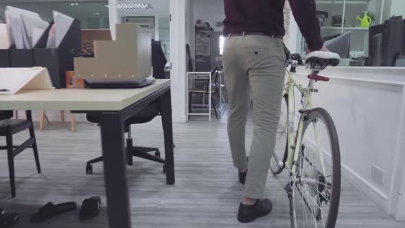 Young Businessman Arriving At Work Pushing Bicycle