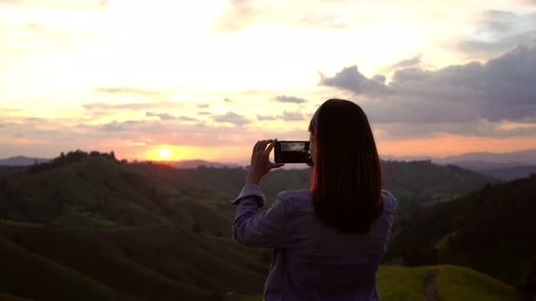 Young woman traveler taking a beautiful sunset over the mountains, Travel lifestyle concept