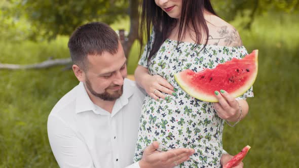Handsome Man Kissing Pregnant Belly of His Charming Wife on Fresh Air alt