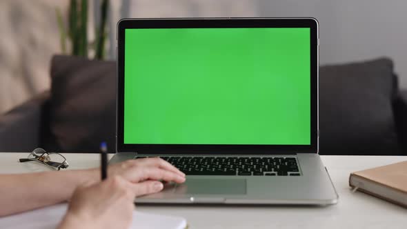 Student Girl Looking at Green Screen Laptop Computer in Living Room Watching Education Video Content