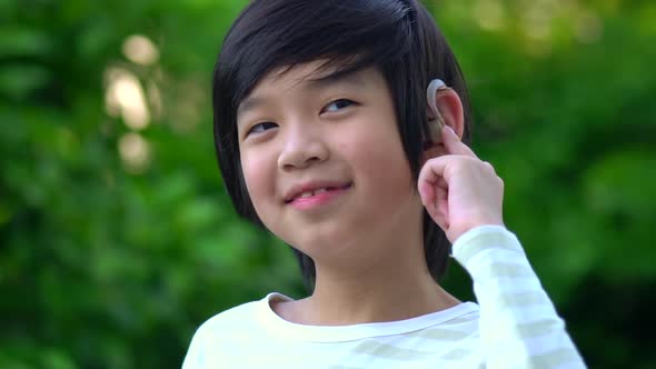 Asian Child With Hearing Aid Behind The Ear Outdoors alt