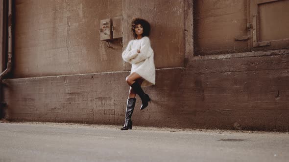 Smiling Woman With Windswept Afro In Woollen Dress And High Heeled Boots alt