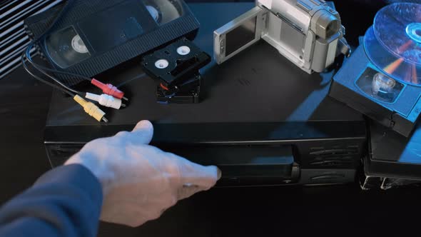 Man Putting Tape Into VHS Video Player alt