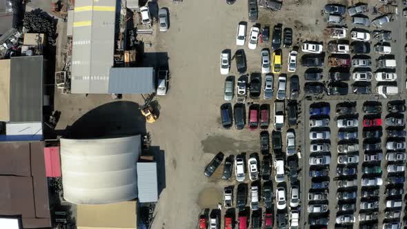 Aerial view flying over a scrapyard full of wrecked cars. alt