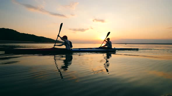 People Are Navigating Canoes Across the Lake at Sunset alt
