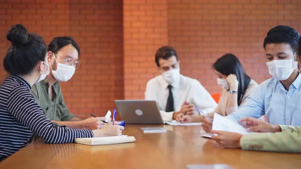 Group of Asian young business people wear face mask and working on computer in office workplace. alt