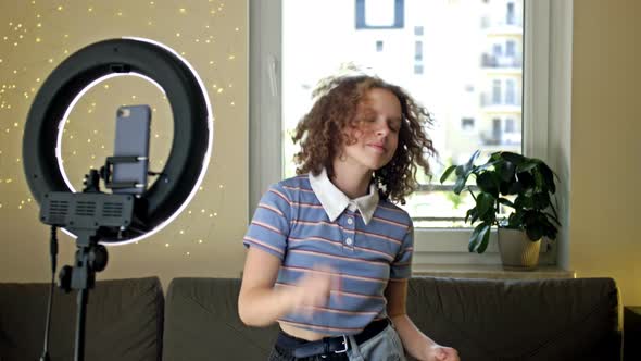 Cheerful Teen Girl Dancing at Camera Filming Video Using Phone on Tripod at Home Creating Her Trendy alt