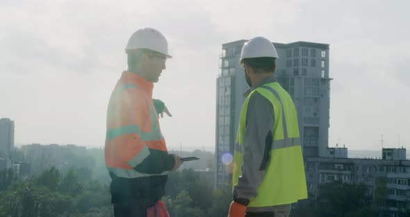 Contactors with Tablet Talking on Top of Building alt