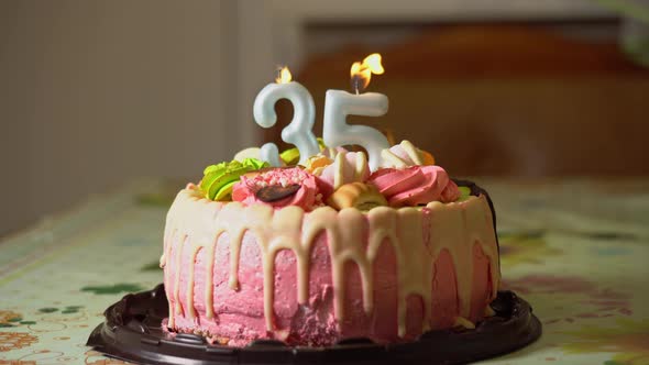 Blowing out candles on a birthday cake. 35th birthday. Birth cake with a burning birth candle alt