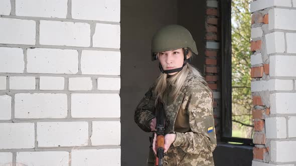 Woman in Uniform in Zone of Armed Conflict Aims with Assault Rifle From Doorway alt