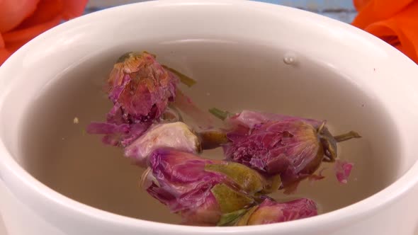White cap of  tea with fragrant dried rose buds, fresh rose flowers alt