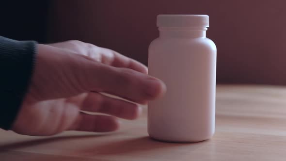 Man Takes a White Bottle of Medicine alt