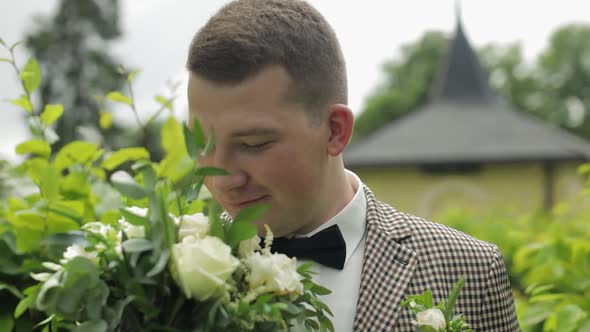 Groom, Young Man in the Green Summer Park with a Wedding Bouquet. He Waiting for His Beloved Bride alt