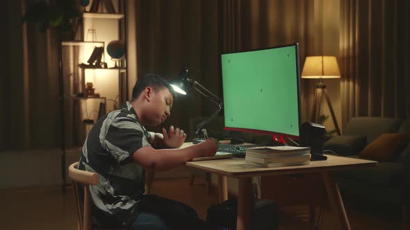 Bored Asian Boy Student Distance Learning With Mock Up Computer Green Screen From Home alt