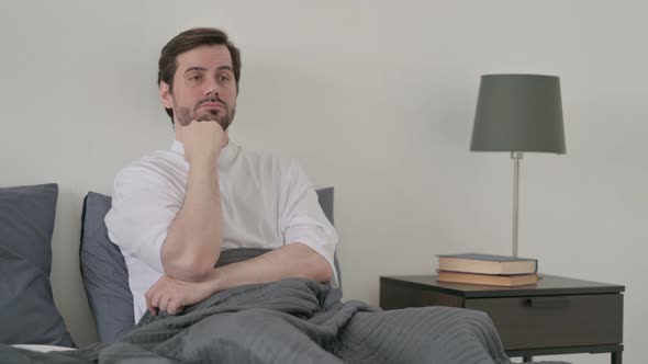 Young Man Taking Nap While Sitting in Bed alt