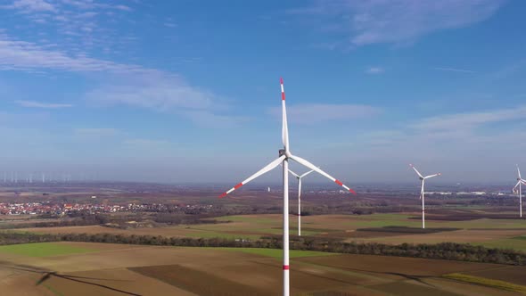 Drone video of a flight through a wind farm with several rotating wind turbines alt
